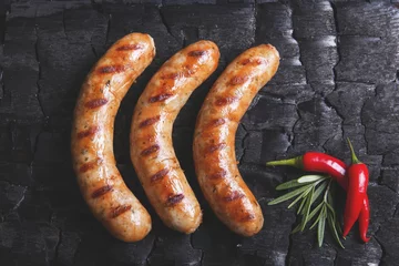 Photo sur Plexiglas Grill / Barbecue Grilled sausages on a black background of charcoal. Barbecue grill
