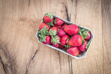 Frische rote Erdbeeren in Körbchen, Holzuntergrund, Draufsicht