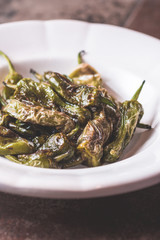 Green Padron Peppers with Olive Oil in Rustic White Plate. Pimientos de Padron.