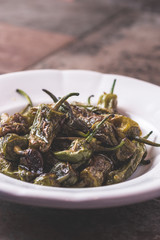 Green Padron Peppers with Olive Oil in Rustic White Plate. Pimientos de Padron.