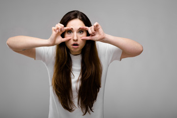 Portrait of emotional puzzled plus size model standing in studio looking in camera showing funny gesture