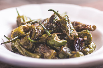 Green Padron Peppers with Olive Oil in Rustic White Plate. Pimientos de Padron.