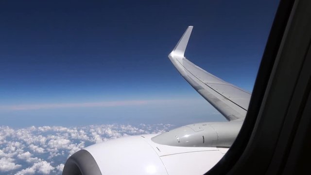 4K. View of wing and airplane engine above beautiful clouds. Travel in aircraft. POV of the passenger tourist traveling around the world-Adrian