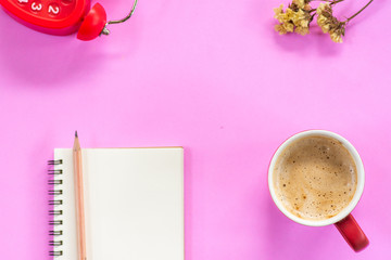 Blank notebook with pencil , morning coffee, alarm clock and dried little flowers on pink background with copy space, morning desk office concept
