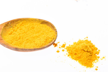 Spoon filled with ground curcuma powder. Condiments and spices concept. Spoon with spice as curcuma, yellow powder on white background, close up. Spoon made out of wood full of spice