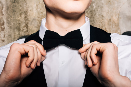 stylish bridegroom in black checkered tuxedo corrects butterfly on neck.Business Concept