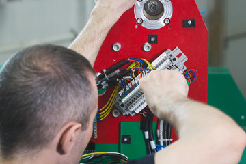 Electrician on overalls is working with energy panel and machinery equipment on plant