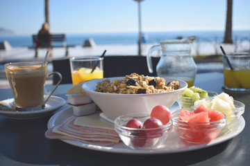 Fototapeta na wymiar Desayuno saludable con frutas y muesli en una cafetería con vistas al mar