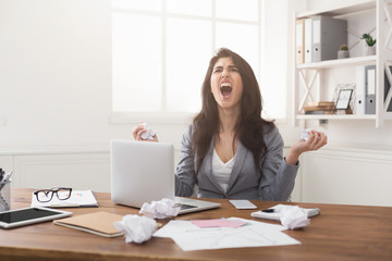 Angry businesswoman working with laptop at office