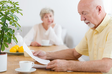 Worried elderly man reading the notification of payment of debt