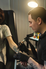 Professional tattoo artist making tattoo on hand