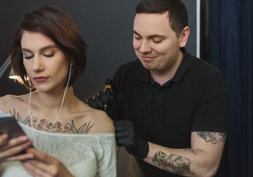 Woman listening to music while doing tattoo