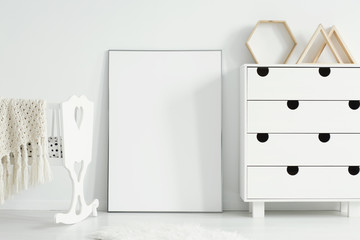 Mockup of empty poster between white cradle and cabinet in simple kid's room interior. Real photo. Paste your poster here © Photographee.eu