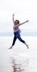 Fototapeta na wymiar Ukrainian woman jumping joyfully on the shore of the beach