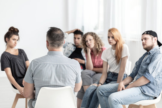 Group of young people talking with psychologist in the rehab center
