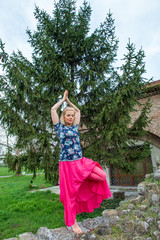 Attractive blond mature woman doing yoga poses outdoor in park, enjoying nature and fresh air. Tree pose - Vrksasana.  Longevity concept
