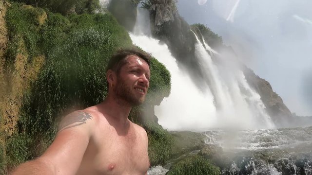 Selfie man. Male taking Self Photo Vlog under Waterfall