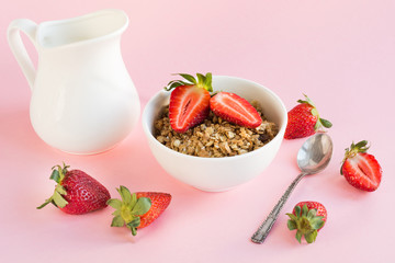 Healthy breakfast of granola, strawberry and milk on pink. Summer.