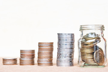 Glass of coin and four pole range of coins on vintage blurred background - Saving money concept.
