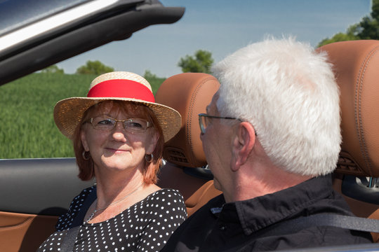 Happy Older Couple Drives With A Luxury Convertible Car