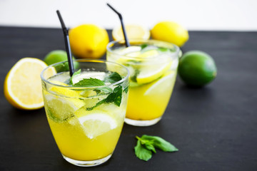 Refreshing lemonade in glass with limes, lemons and mint. Summer drinks