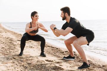 Happy young sport couple doing squats