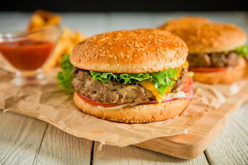 Burgers with grilled beef, salad, cheese and tomato on dark background