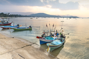 Naklejka premium Traditional Thai fishing boats in the sunset preparing for night hunt