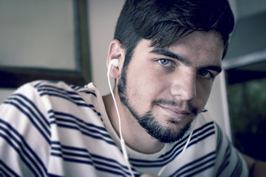 Portrait of trendy bearded young man with ear phones. Color graded image.