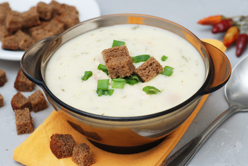 Cream Soup with Chicken Meat and Bread Crackers Croutons Orange Napkin Gray Textured Background