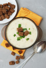 Cream Soup with Chicken Meat and Bread Crackers Croutons Orange Napkin Gray Textured Background