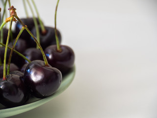 Cherry in a bowl on a white table. Ripe juicy cherry on a light background.