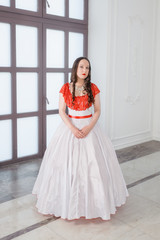 Beautiful woman in white and red medieval dress with crinoline