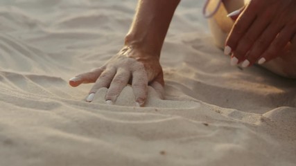 Hand of young unidentified girl touching sand