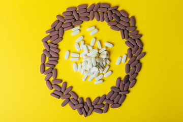 a lot of violet, oval tablets, pills scattered, scattered on a yellow background in the form of a circle, in the middle of the circle are scattered white pills, oval, space for text