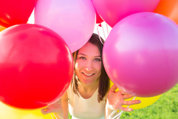 Fototapeta na wymiar Summer party. Smiling girl looking through colorful air balloons close-up portrait. Happiness concept. Birthday celebration.