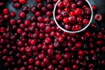 Cherries with a small metal bucket on a grey concrete background, summer berries concept with copy space. Neutral color tones still life