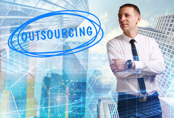 The concept of business, technology, the Internet and the network. Young businessman showing inscription: Outsourcing
