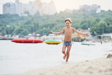 Happy cheerful boy running along sandy beach © Denys Kurbatov