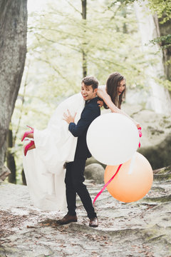 Young funny happy wedding couple outdoors with ballons