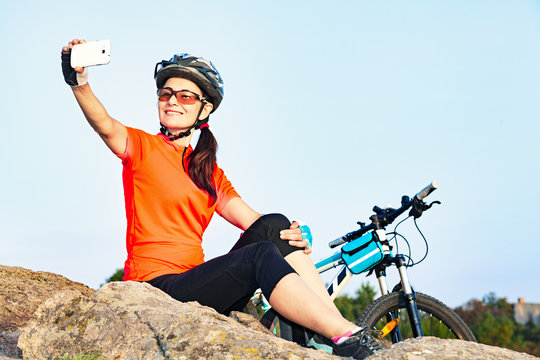  Adult attractive female cyclist on relaxation taking a selfie photo outdoor.