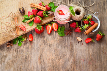 Strawberry smoothies in glass with many strawberries on wooden background. Top view. Copy space