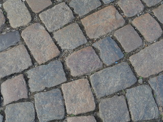 roughly carved pavement stones, laid with wide joints,different shades of gray of the stones
