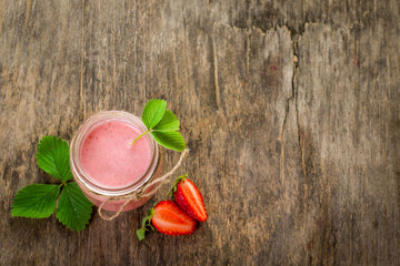 Strawberry smoothies in glass on wooden background. Top view. Copy space