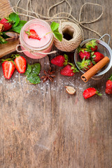 Strawberry smoothies in glass with many strawberries on wooden background. Top view. Copy space