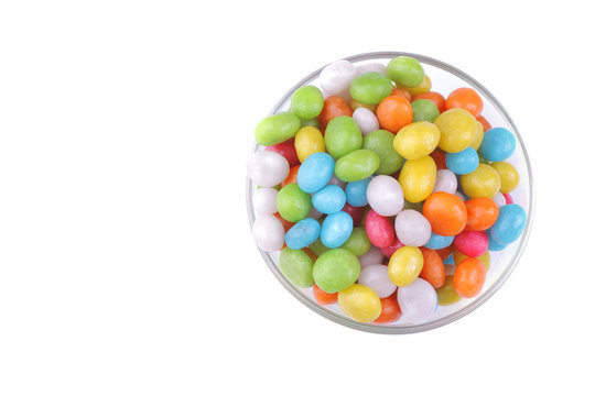 Multicolored round candy in a glass bowl on a white background. Top view. Isolated.