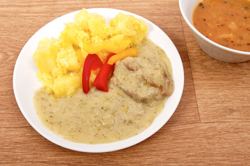 Seitan with dill sauce and potatoes on a table