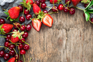 Fresh sweet cherries and strawberries on wooden background. Top view. Copy space. Flatlay