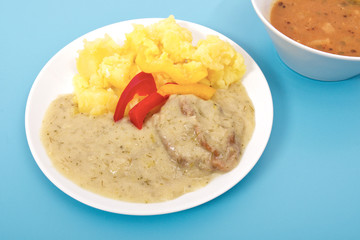 Seitan with dill sauce and potatoes on a blue