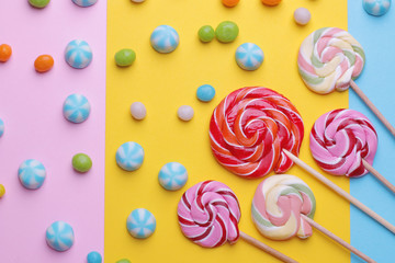 Multicolored round candy and colored lollipops on colored bright backgrounds. Top view